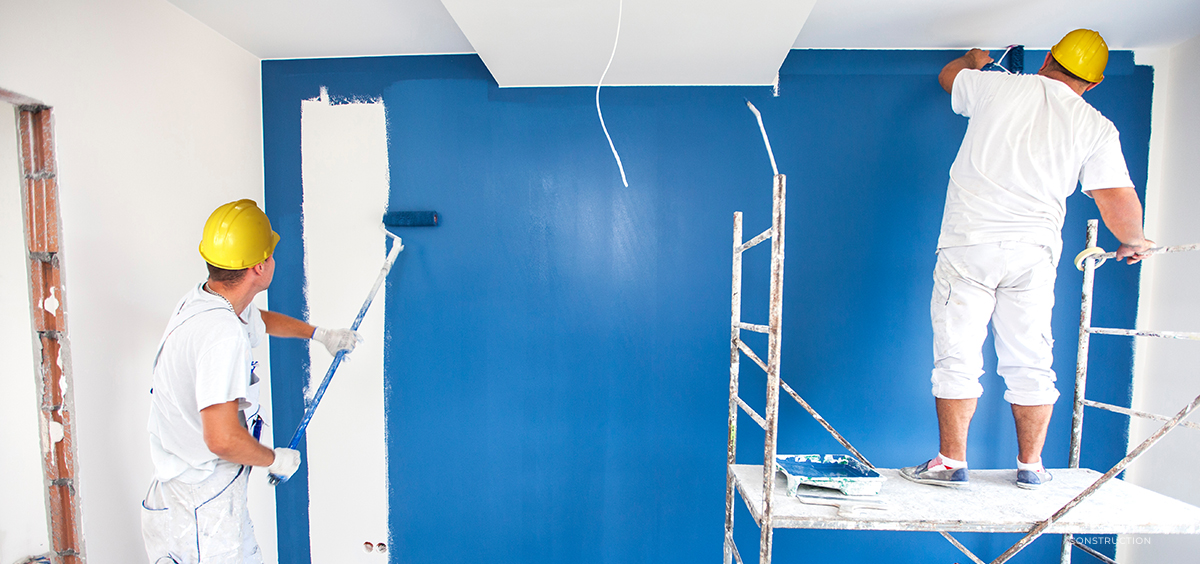 A man paints a wall blue