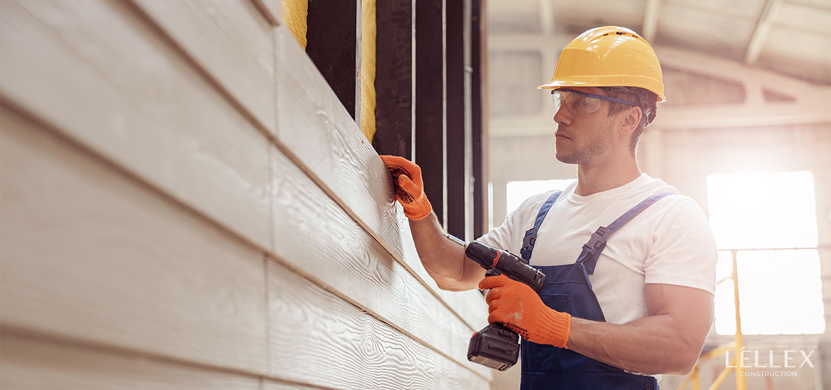 A man sheaths a house with siding