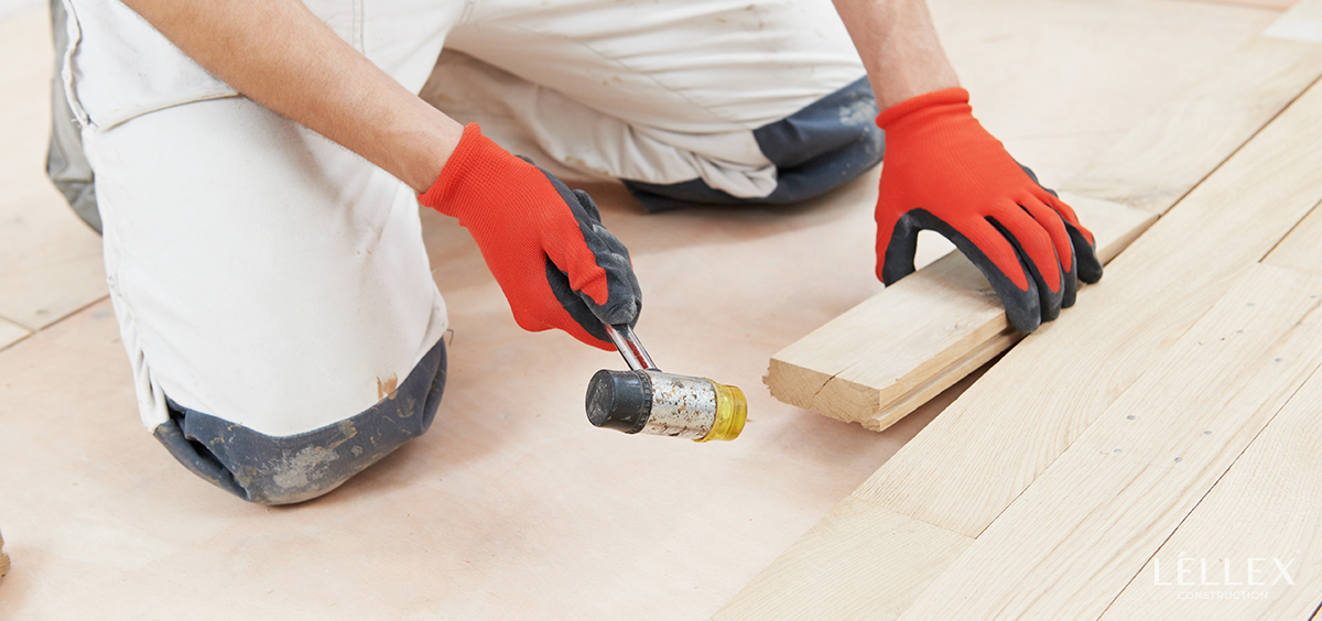 a man installs new parquet with a hammer