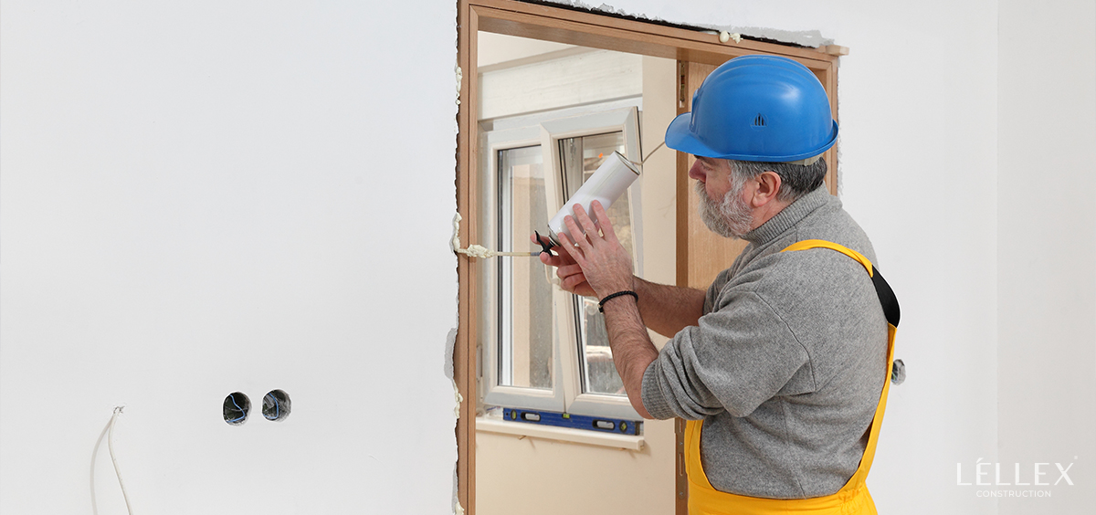 A man blows foam into the hole between the door frame and the doorway