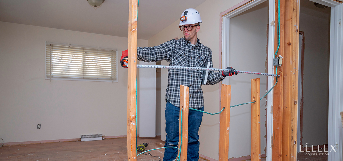 A builder takes measurements in a house