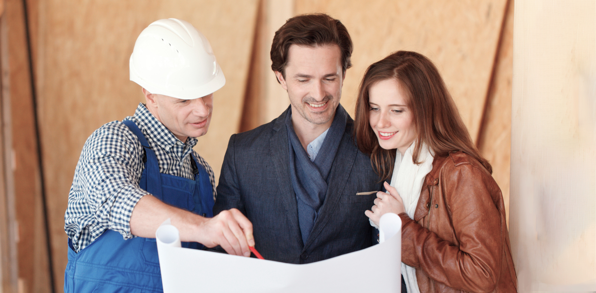 A builder shows a young couple a plan for their future home.